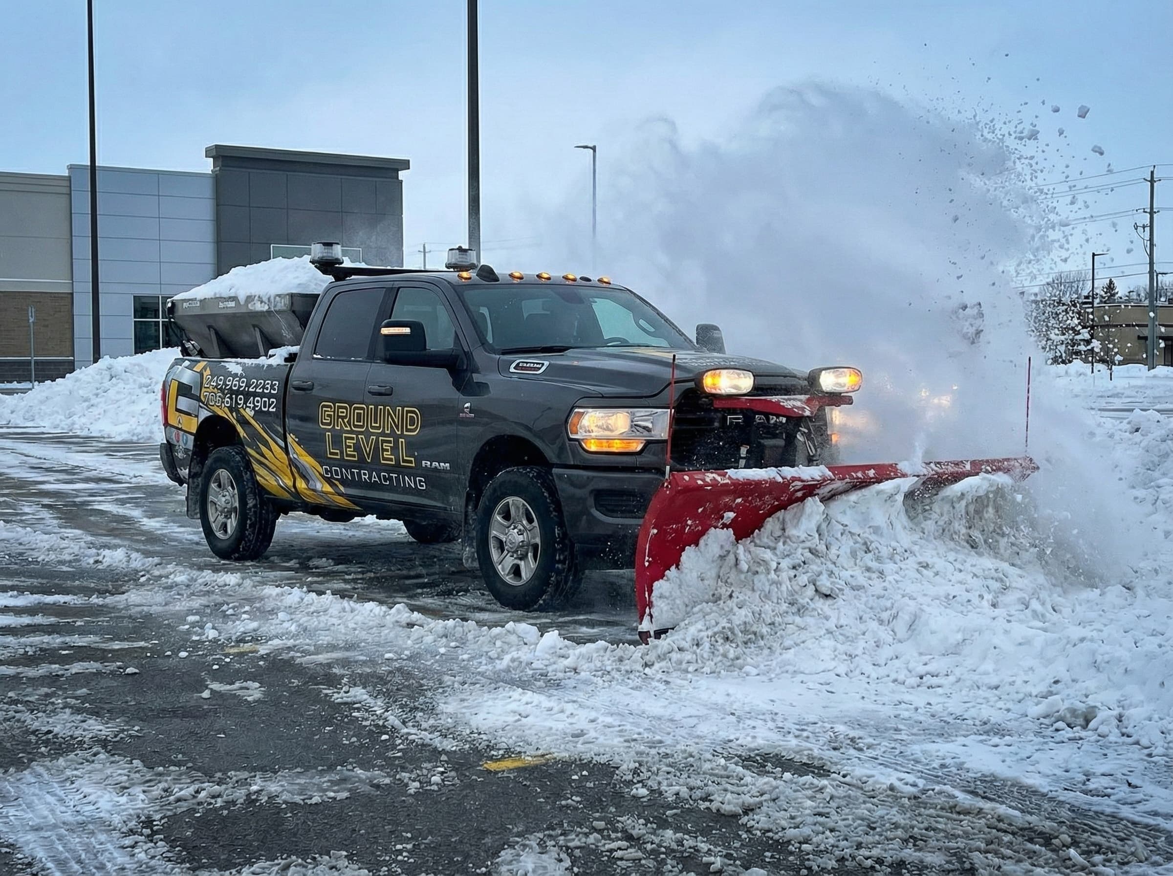 Commercial Parking Lot Snow Plowing — Barrie & Simcoe County — Branded Ground Level Contracting plow truck with salt spreader on a commercial property in Simcoe County